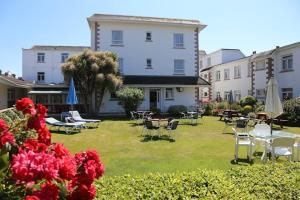 un patio con sillas y mesas y un edificio en Runnymede Court Hotel, en Saint Helier Jersey