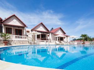 a large swimming pool in front of a house at Hong Bin Bungalow in Phú Quốc