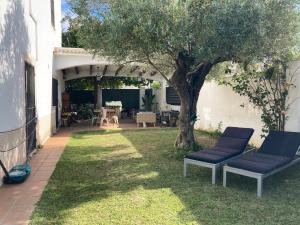 a patio with two chairs and a tree in a yard at Casa ChillOut a 6km de Sevilla Piscina comunitaria in Valencina de la Concepción