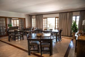 a dining room with tables and chairs and windows at Duiker Game Lodge in Hluhluwe