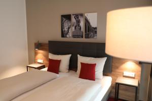 una camera da letto con un letto bianco con cuscini rossi di Hotel INCLUDiO a Ratisbona