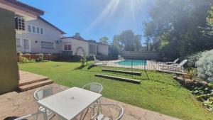 een achtertuin met een tafel en stoelen en een zwembad bij Teilen in Villa General Belgrano
