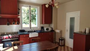 a kitchen with red cabinets and a table in it at Le Balcon sur la Meuse in Revin