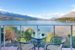 a table and chairs on a balcony with a view of a lake at Spinnaker Bay - Lakeview Apartments in Queenstown