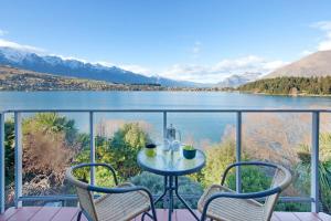 a table and chairs on a balcony with a view of a lake at Apartments at Spinnaker Bay in Queenstown