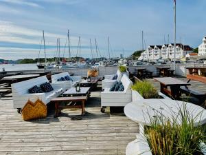 eine Gruppe von Tischen und Sofas auf einem Dock mit Booten in der Unterkunft Hummeren Hotel in Tananger