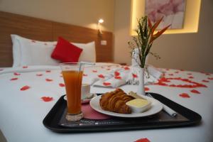 uma bandeja com comida e uma bebida numa cama em HOTEL ASTRAL em Abidjan