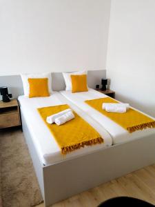 Evita Studio Apartment في كارلوفاتش: سرير ابيض كبير عليه مخدات صفراء