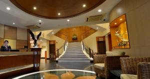a lobby with a staircase with chairs and a glass table at Asiana Hotel in Kota Kinabalu
