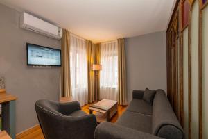 a living room with a couch and chairs and a tv at Suites İstanbul in Istanbul