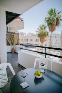 a table with a bowl of grapes and wine glasses on a balcony at Lazaros Centre Apartment in Larnaka