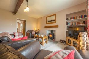 sala de estar con sofá de cuero y chimenea en West Shaw Cote Cottage en Leyburn