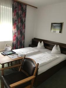 クルンペンドルフ・アム・ヴェルターゼーにあるHOTEL Jerolitschのベッド2台、椅子、テーブルが備わる客室です。
