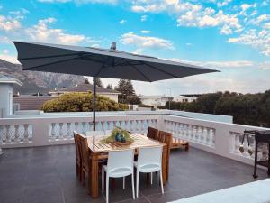 a table and chairs on a balcony with an umbrella at Villa Voigt in Hermanus +10 photos
