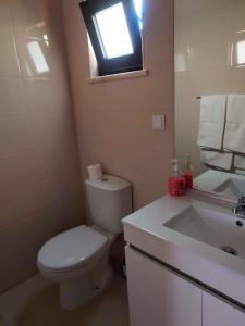 uma casa de banho com um WC, um lavatório e uma janela em Quinta da Norinha em Portimão