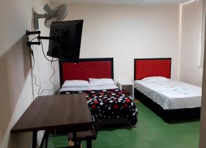 a room with two beds and a tv and a table at Hotel Majestic in Ocaña