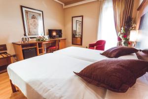 1 dormitorio con 2 camas blancas y escritorio en Hotel Bardo Recoletos Coco en Salamanca