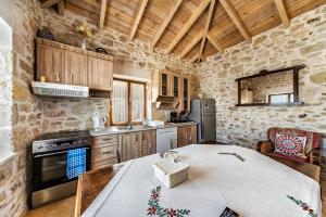 a kitchen with a table in a room with stone walls at GUEST HOUSE APHRODITE in Káto Arkhánai