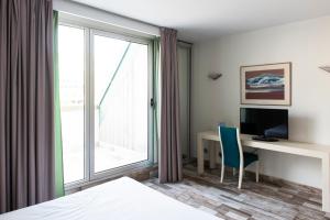 a room with a bed, chair, desk and a window at Sercotel Hotel Palacio del Mar in Santander