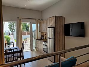 a kitchen with a refrigerator and a table with chairs at Aphrodite's Apartments in Artemida