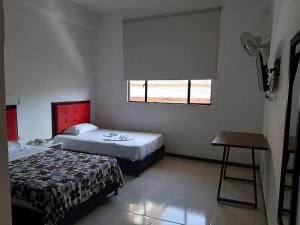 a bedroom with two beds and a table and a window at Hotel Majestic in Ocaña