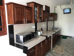a kitchen with wooden cabinets and a microwave at Coral Palm Villa and Apartment in Unawatuna
