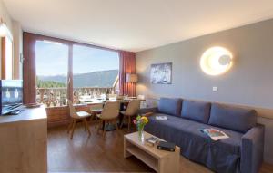 a living room with a blue couch and a dining room at Résidence Odalys Le Buet in Morillon