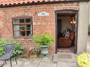 uma casa de tijolos com uma cadeira e um sofá em Woldsend Cottage em Horncastle