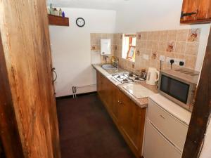 uma pequena cozinha com um fogão e um lavatório em Woldsend Cottage em Horncastle