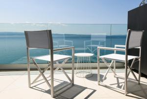 two chairs and a table on a balcony overlooking the water at Gallery Luxury Suites & Rooms-Only Adults in Split