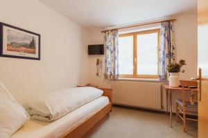 a bedroom with a bed and a desk and a window at Haus Albona in Klösterle