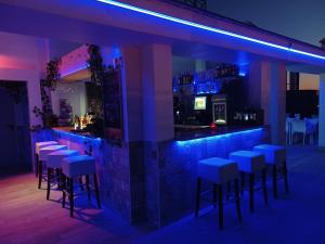 un bar con taburetes en una habitación con iluminación púrpura en Puerta Salinas Isla Cristina, en Isla Cristina