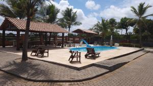 a swimming pool with chairs and a table and a swing at Pousada do Rancho in Barreirinhas