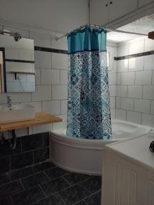 a bathroom with a tub and a sink and a shower curtain at Aquarius Hotel in Fourka