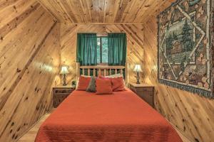 a bedroom with a bed in a room with wooden walls at Cozy Maggie Valley Cabin with Deck and Private Hot Tub in Maggie Valley