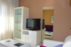 a living room with a tv on a white cabinet at Pensión Quilmes in Vimianzo