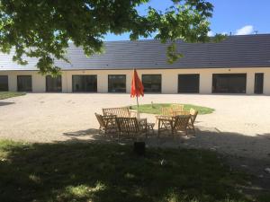 una mesa y sillas con sombrilla frente a un edificio en Domaine des Bois Argentés, en Saugirard