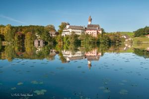 um reflexo de um edifício sobre um lago com árvores em Haus Christ em Anger