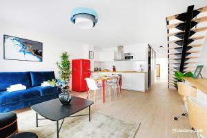 a living room with a blue couch and a kitchen at CMG Gaite - Montparnasse in Paris