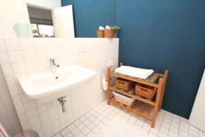 a bathroom with a white sink and a blue wall at Modern & Friendly Apartment Ammersee in Windach