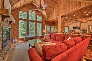 a living room with a red couch and a fireplace at Luxury Cabin with Hot Tub about 3 Miles to Hochatown! in Broken Bow