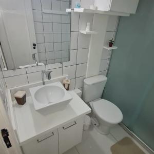 a white bathroom with a sink and a toilet at Apartamento Praia do Forte in Mata de Sao Joao