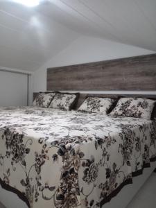 a large bed with a black and white comforter and pillows at Apartamento Praia do Forte in Mata de Sao Joao