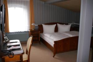um quarto com uma cama, uma secretária e uma janela em Eisenbahnromantik Hotel em Meyenburg
