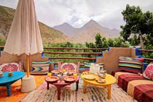 een patio met een tafel en stoelen met bergen op de achtergrond bij Jnane Karma in Imlil