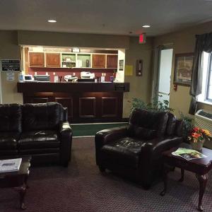 a living room with leather furniture and a bar at Osceola Grand Hotel in Evart