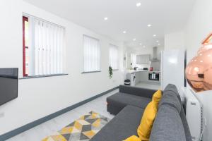 a living room with a gray couch and a kitchen at Nottingham City Centre Short Stay Apartments with Parking in Nottingham