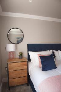 a bedroom with a bed with a blue headboard and a mirror at 10 Bootham House - luxury city centre apartment with free parking for one car in York