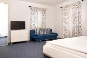 a bedroom with a bed and a tv and a blue couch at Hotel Villa Martino - zum Hirsch in Bad Säckingen
