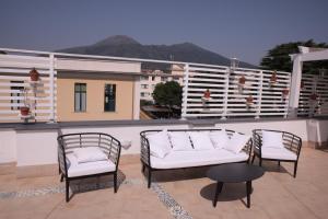 een patio met witte stoelen en een tafel op een balkon bij Palazzo Caracciolo del Sole in Terzigno